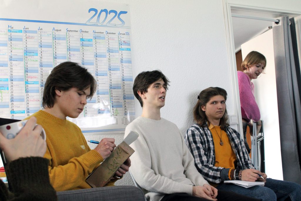 Teilnehmende des Debattierclubs diskutieren und machen sich Notizen während des Treffens