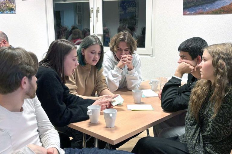 Junge Teilnehmende diskutieren im Team beim Quizabend „Eine Minute zum Nachdenken“
