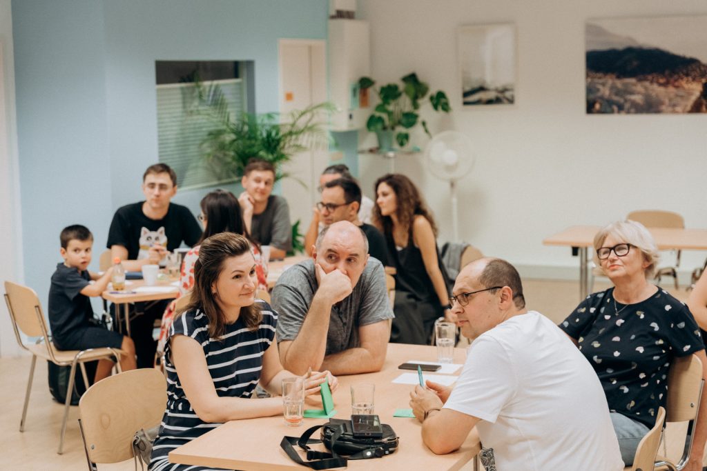Teilnehmende sitzen in Teams und diskutieren beim Quizabend „Eine Minute zum Nachdenken“