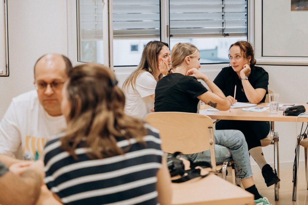 Teilnehmende diskutieren konzentriert in kleinen Gruppen beim Quizabend „Eine Minute zum Nachdenken“
