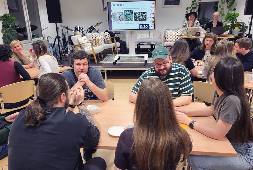Teilnehmende beim zweisprachigen Quiz Event in Fellbach sitzen an Tischen und diskutieren Fragen aus Fantasy-Welten